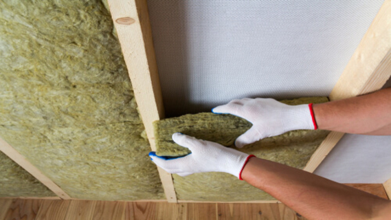 Close-up of worker hands in white gloves insulating rock wool insulation staff in wooden frame for future walls for cold barrier