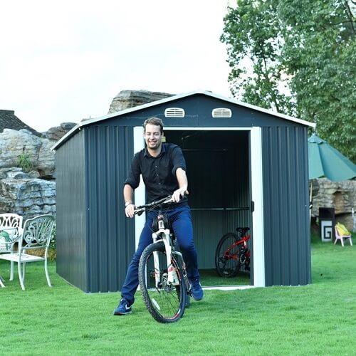 A man sitting on a bike in front of a garden shed